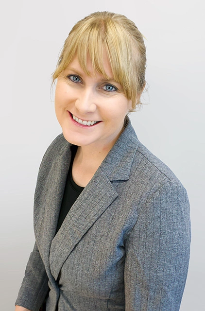 A woman in a gray jacket smiling for the camera.