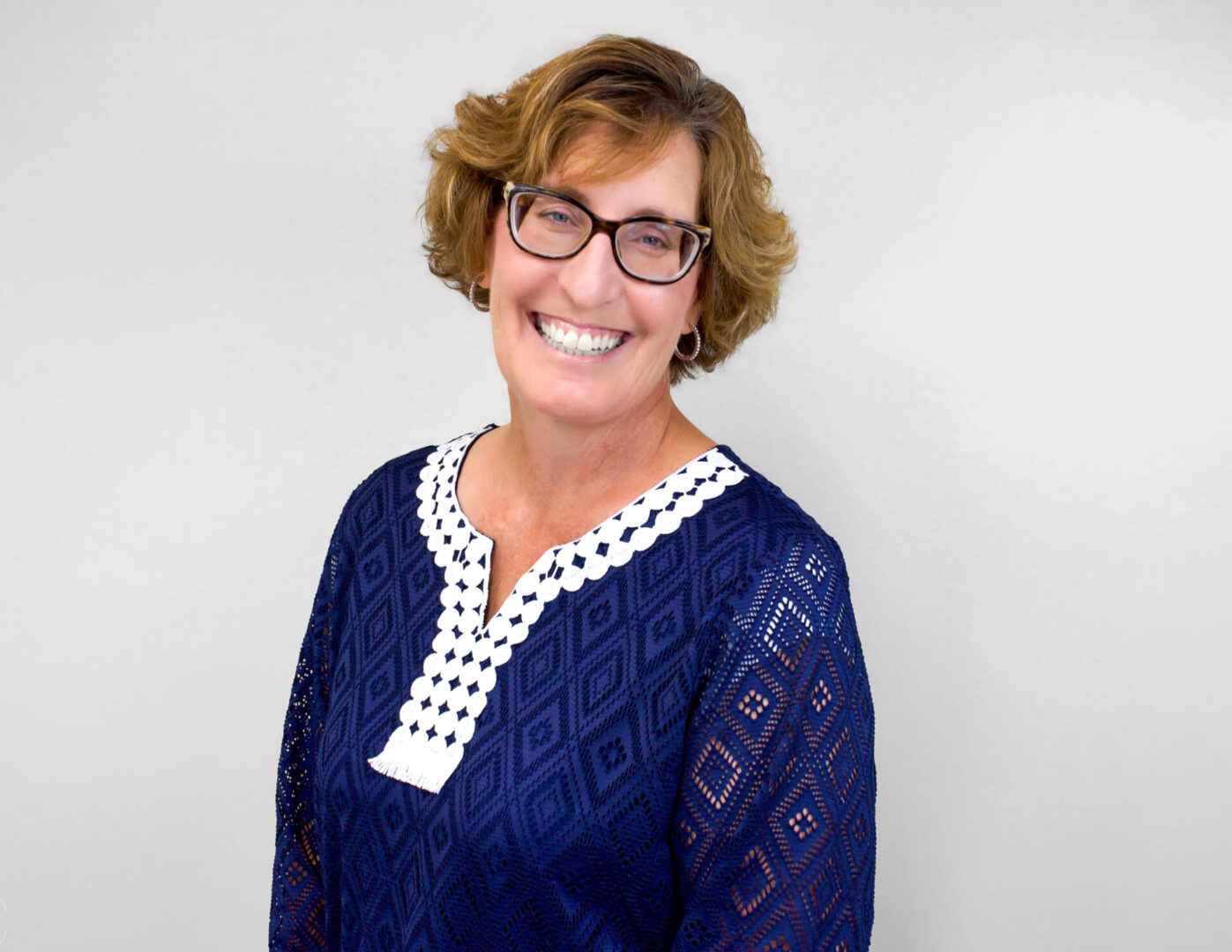 A woman in blue shirt smiling for the camera.